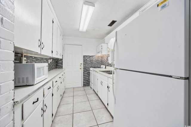 kitchen with white cabinets, a textured ceiling, white appliances, decorative backsplash, and light tile patterned floors