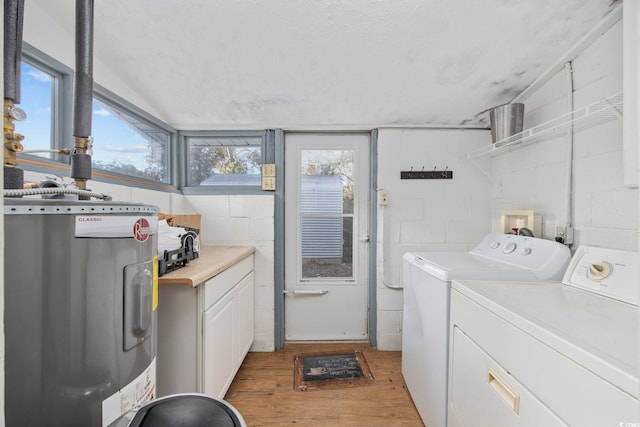 clothes washing area with cabinets, hardwood / wood-style floors, washing machine and dryer, and water heater