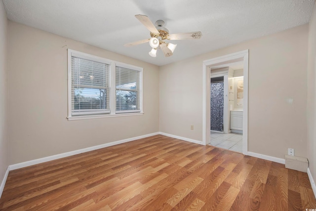 spare room with a textured ceiling, light hardwood / wood-style floors, and ceiling fan