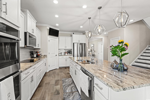 kitchen featuring a large island with sink, white cabinetry, decorative light fixtures, and appliances with stainless steel finishes