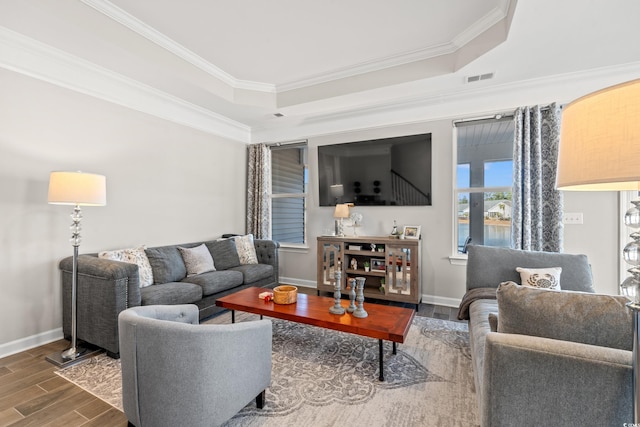 living room featuring wood-type flooring, a tray ceiling, and ornamental molding