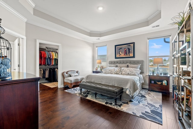 bedroom featuring a spacious closet, dark hardwood / wood-style floors, and ornamental molding