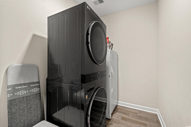 washroom featuring hardwood / wood-style flooring and stacked washer and dryer