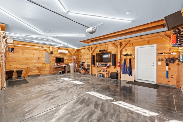 garage with a workshop area, electric panel, a garage door opener, and wooden walls