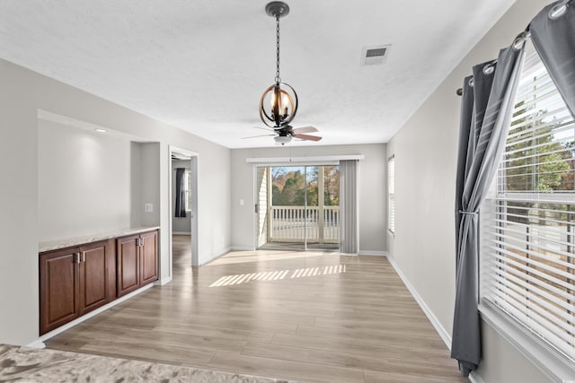 interior space with a textured ceiling, light wood-type flooring, and ceiling fan