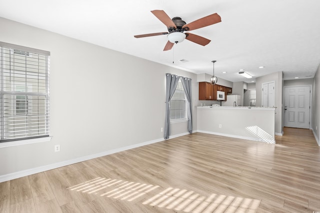 unfurnished living room featuring ceiling fan and light hardwood / wood-style flooring