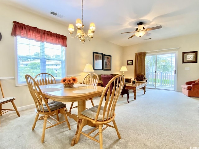 carpeted dining area with ceiling fan with notable chandelier