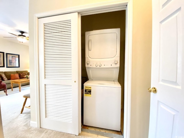 clothes washing area with stacked washer and dryer, ceiling fan, and light colored carpet