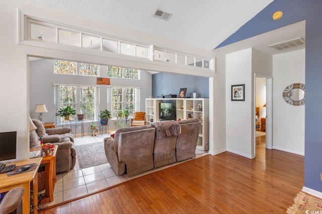 living room with vaulted ceiling, a textured ceiling, and light wood-type flooring