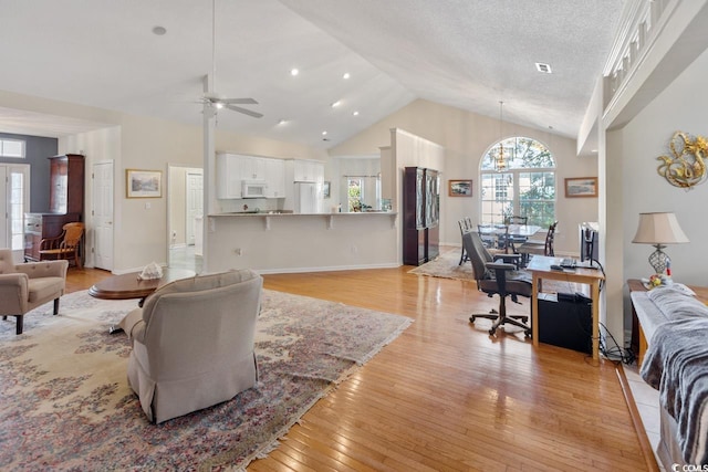 living room with a textured ceiling, high vaulted ceiling, light hardwood / wood-style flooring, and ceiling fan