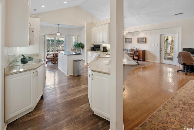 kitchen with white cabinets, decorative light fixtures, a kitchen island, and lofted ceiling