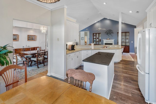 kitchen with a center island, white cabinets, ceiling fan with notable chandelier, white refrigerator, and kitchen peninsula