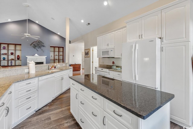 kitchen featuring ceiling fan, dark stone counters, vaulted ceiling, white appliances, and white cabinets