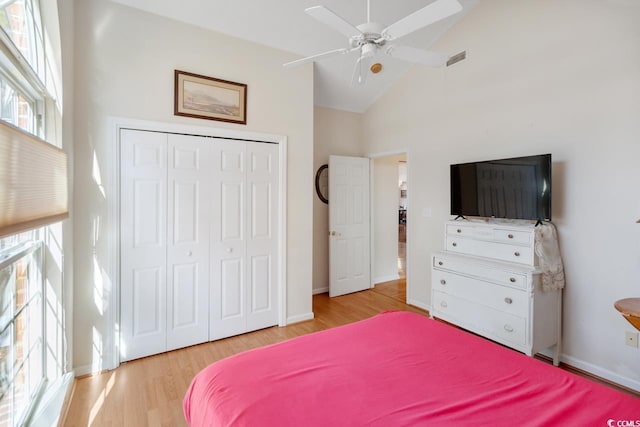 bedroom featuring ceiling fan, light wood-type flooring, high vaulted ceiling, and a closet