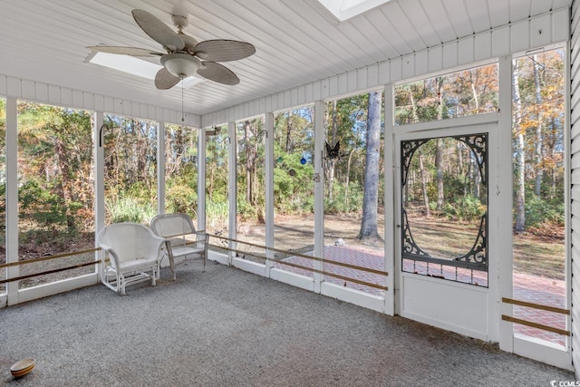 unfurnished sunroom with ceiling fan, a healthy amount of sunlight, and a skylight