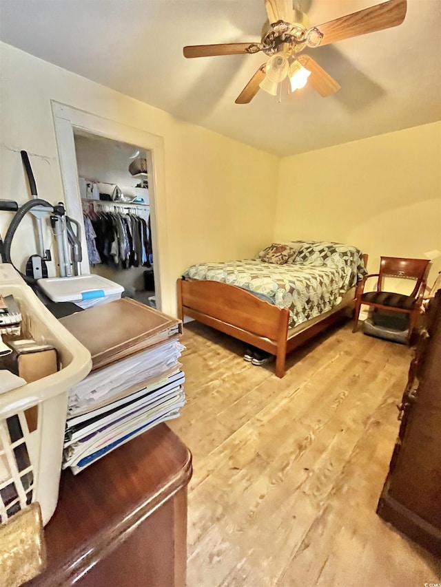 bedroom with light hardwood / wood-style floors, a spacious closet, a closet, and ceiling fan