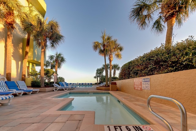 pool at dusk with a patio area