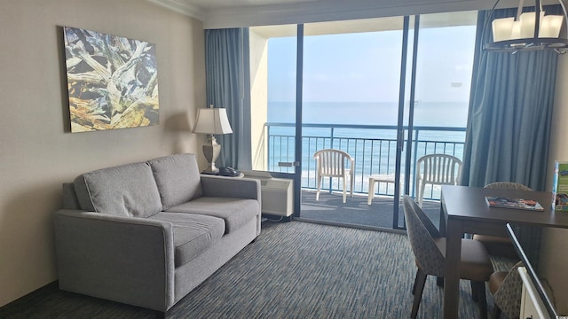 living room featuring dark colored carpet, a water view, a wall of windows, and an inviting chandelier