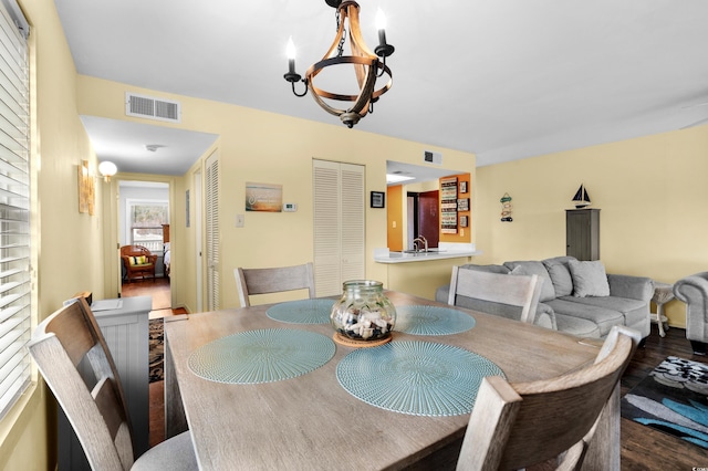 dining area with a chandelier, wood-type flooring, and sink