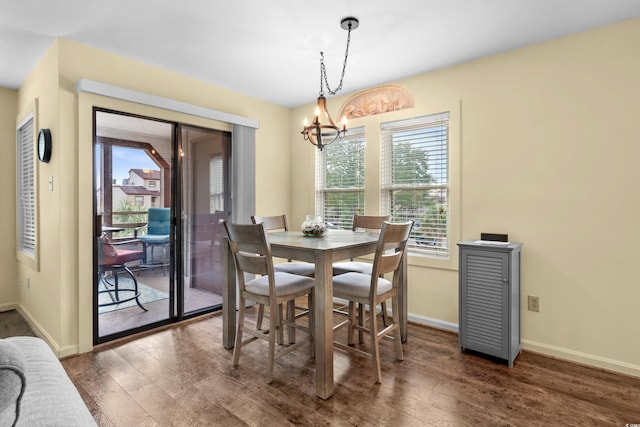 dining space with dark hardwood / wood-style floors, a wealth of natural light, and an inviting chandelier