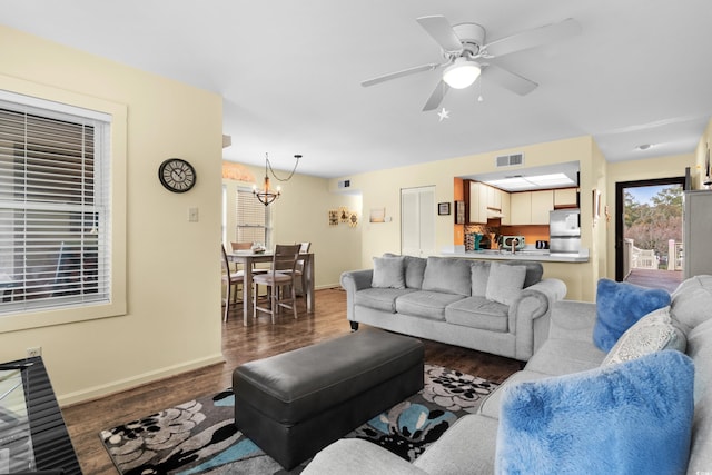 living room featuring ceiling fan with notable chandelier and dark hardwood / wood-style floors