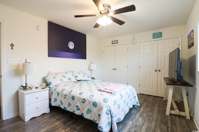 bedroom featuring dark hardwood / wood-style floors, ceiling fan, and multiple closets