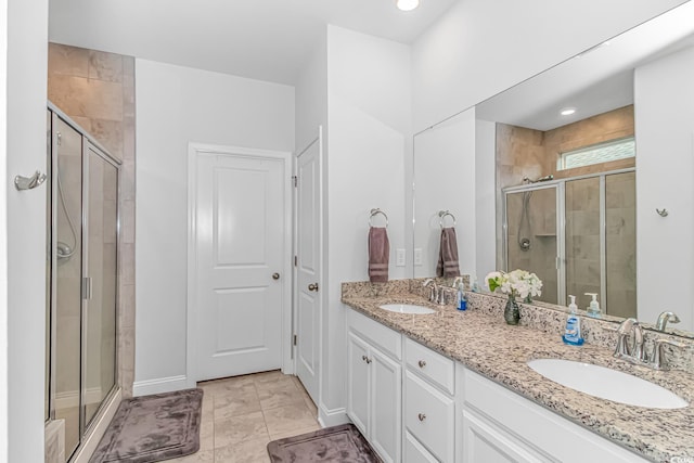 bathroom featuring double vanity, tile patterned flooring, a shower stall, and a sink