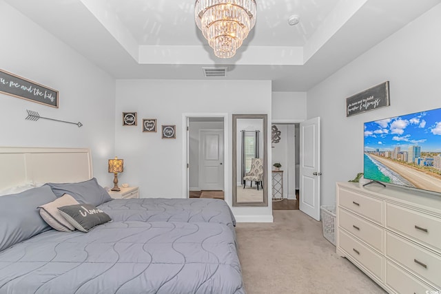 bedroom featuring an inviting chandelier, visible vents, a tray ceiling, and light colored carpet