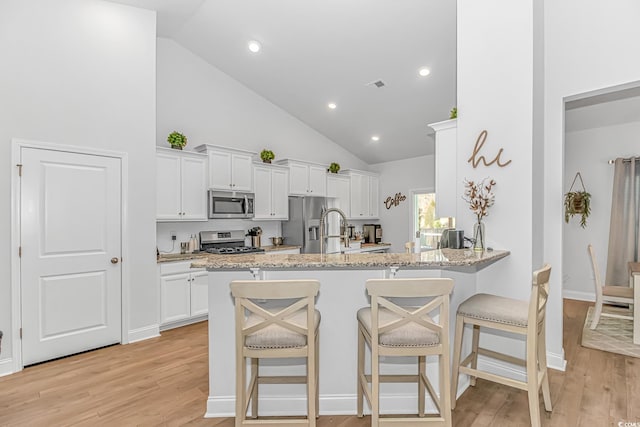 kitchen featuring visible vents, appliances with stainless steel finishes, white cabinets, and a kitchen breakfast bar