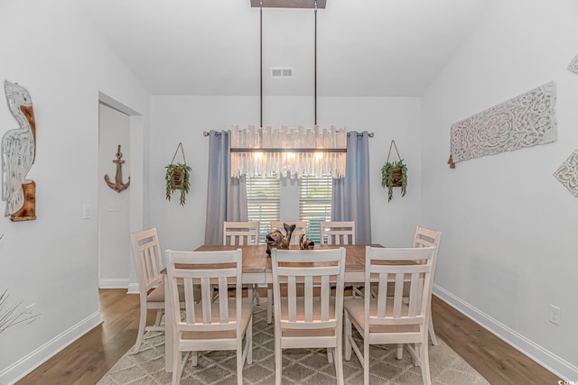 dining room with an inviting chandelier, visible vents, baseboards, and wood finished floors