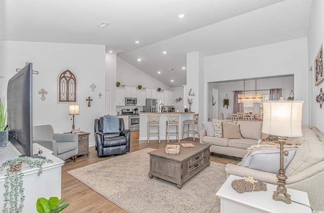 living room with visible vents, high vaulted ceiling, light wood-style flooring, and recessed lighting