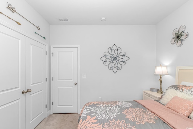 bedroom with a closet, visible vents, and light colored carpet