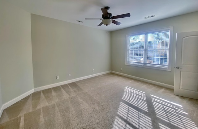 unfurnished room featuring baseboards, visible vents, ceiling fan, and light colored carpet