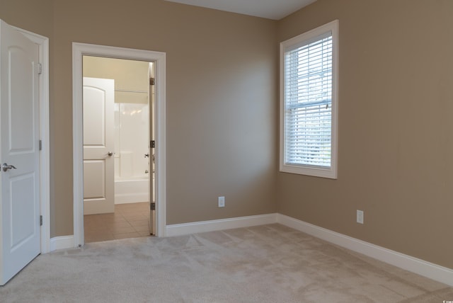 spare room with baseboards, light tile patterned floors, and light colored carpet