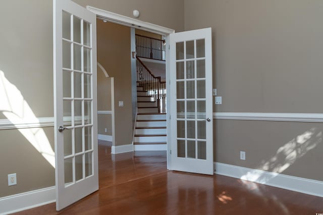 doorway featuring baseboards, arched walkways, stairway, wood finished floors, and french doors