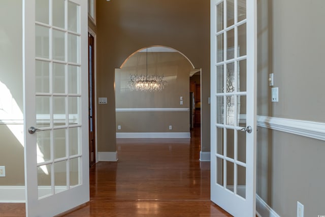 interior space featuring dark wood-style floors, arched walkways, french doors, and baseboards