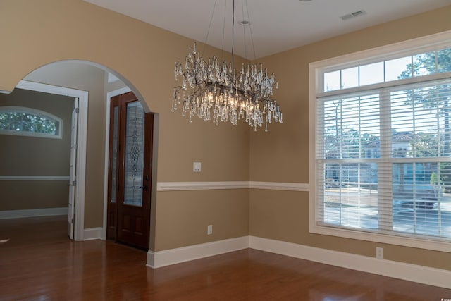 interior space with dark wood-style floors, baseboards, visible vents, and arched walkways