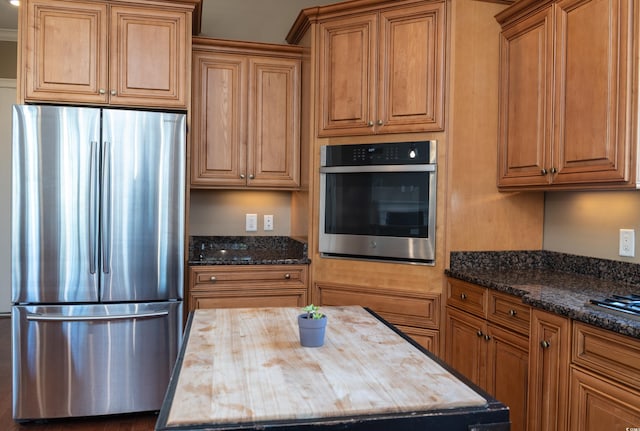 kitchen with appliances with stainless steel finishes, butcher block counters, and brown cabinets