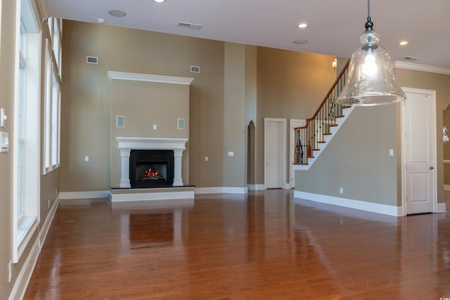 unfurnished living room featuring a warm lit fireplace, visible vents, baseboards, and wood finished floors