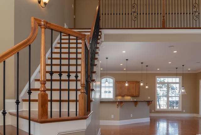 staircase featuring plenty of natural light, baseboards, crown molding, and wood finished floors