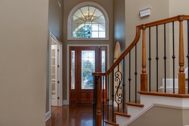 entryway featuring dark wood-style floors, stairs, a towering ceiling, and baseboards