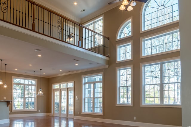 unfurnished living room with crown molding, recessed lighting, visible vents, a high ceiling, and baseboards