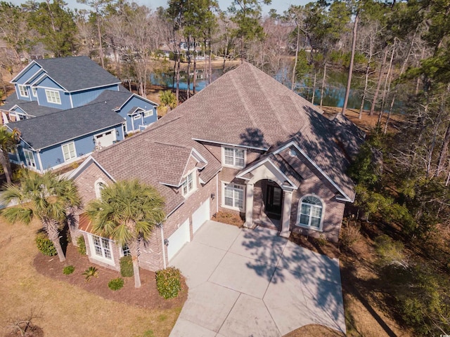 exterior space featuring a shingled roof, concrete driveway, brick siding, and a garage