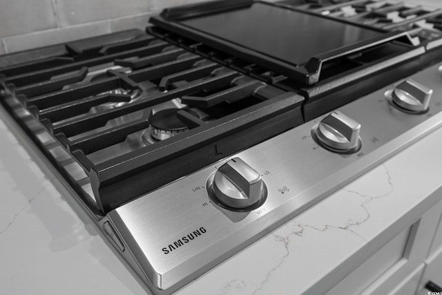 interior details with light stone countertops and stainless steel gas stove