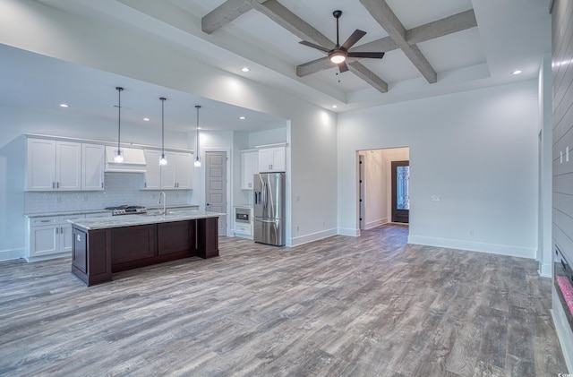 kitchen with a center island with sink, coffered ceiling, hardwood / wood-style flooring, stainless steel fridge with ice dispenser, and white cabinets