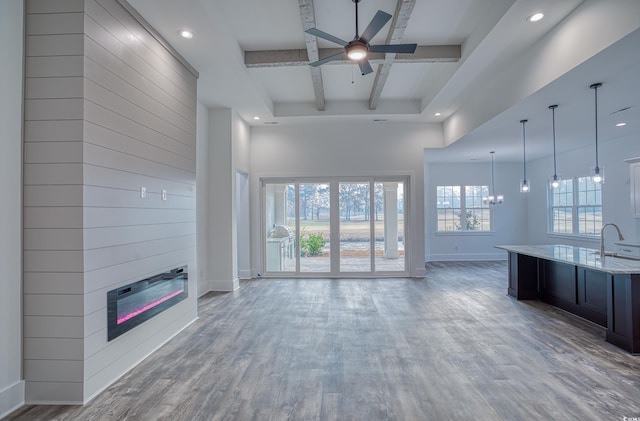 unfurnished living room with ceiling fan, a large fireplace, hardwood / wood-style floors, and sink