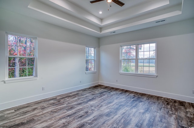 unfurnished room with a raised ceiling, ceiling fan, and dark hardwood / wood-style flooring