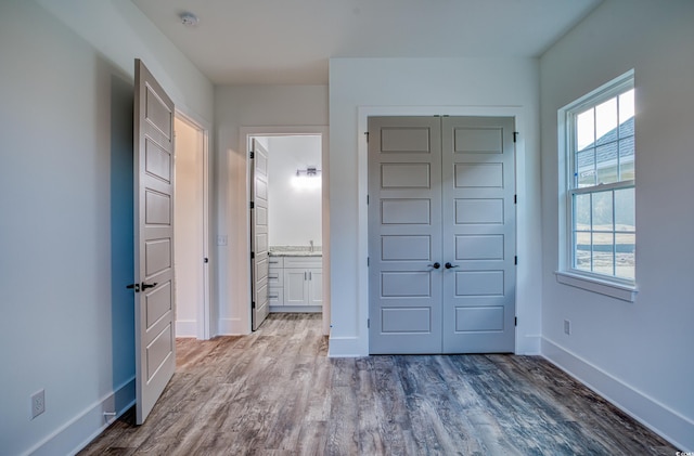 unfurnished bedroom featuring connected bathroom, a closet, and light hardwood / wood-style floors