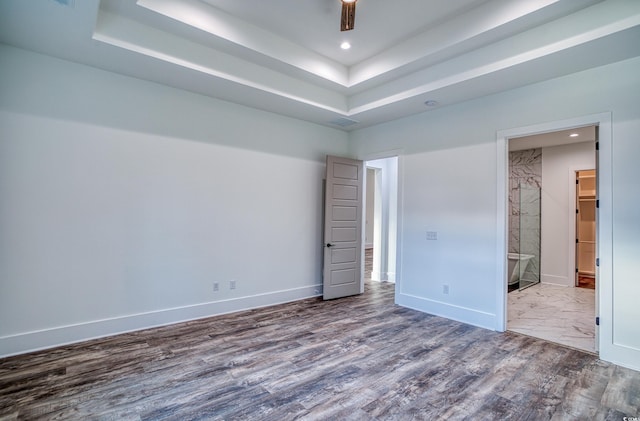 unfurnished room with hardwood / wood-style flooring, ceiling fan, and a raised ceiling