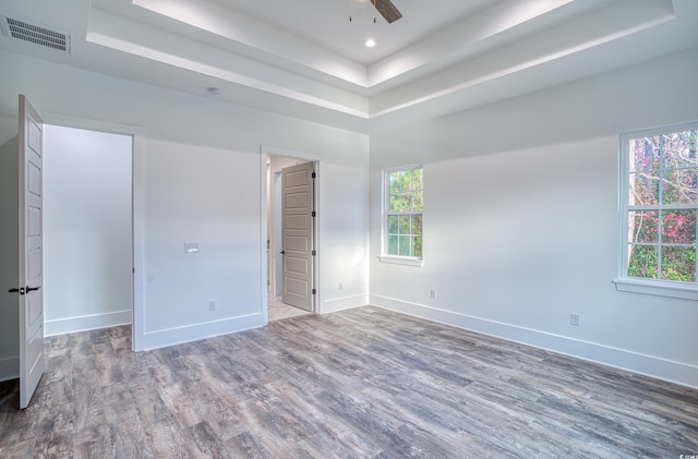 unfurnished bedroom featuring hardwood / wood-style flooring, ceiling fan, and a tray ceiling